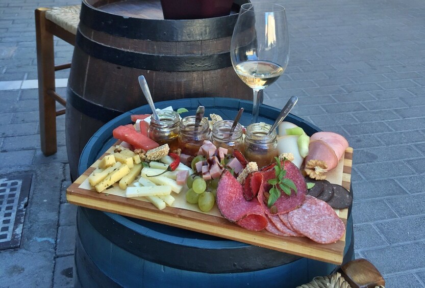 Charcuterie board and glass of wine sit on a wine barrel in Athens, Greece
