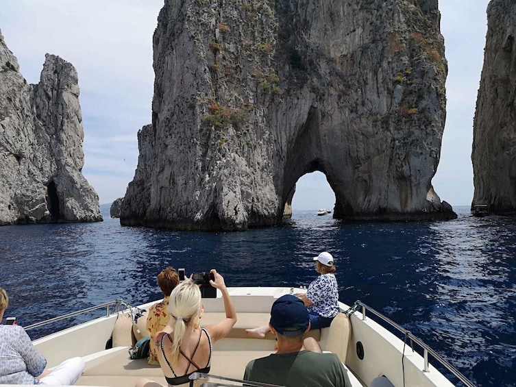 Group on a boat cruising through Faraglioni island in Italy