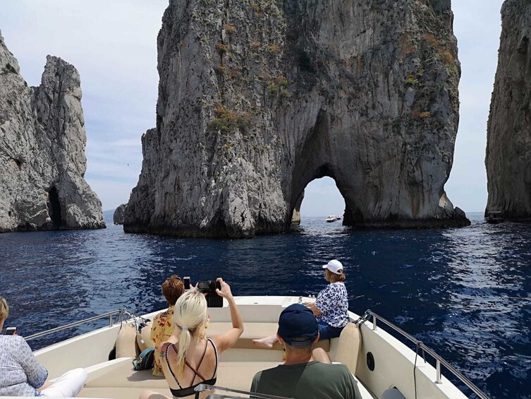 Group on a boat cruising through Faraglioni island in Italy