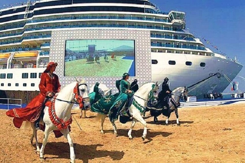 Omani people riding Arabian Horses with cruise ship in the background