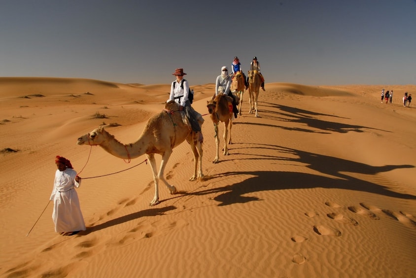 Line of camel riders in the desert in Jamila