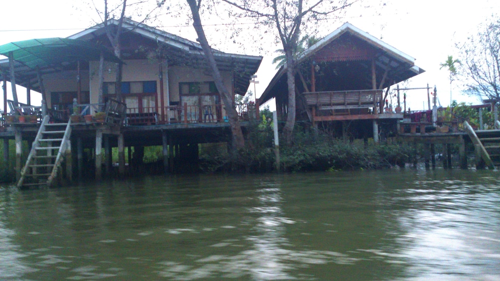 Show item 3 of 11. Two houses on the banks of a river in Maeklong