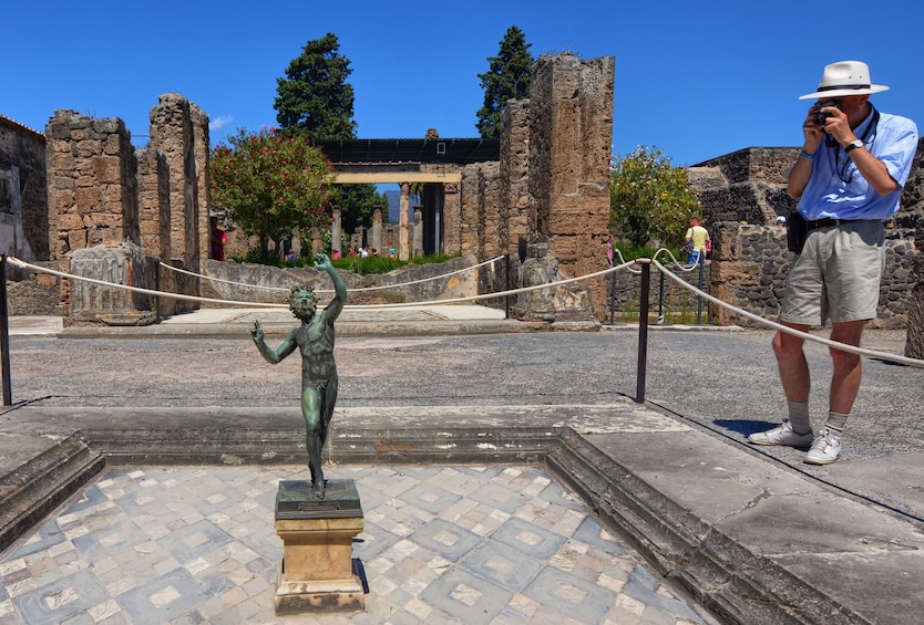 Tourist takes photo of dancing faun statue in Pompeii, Italy
