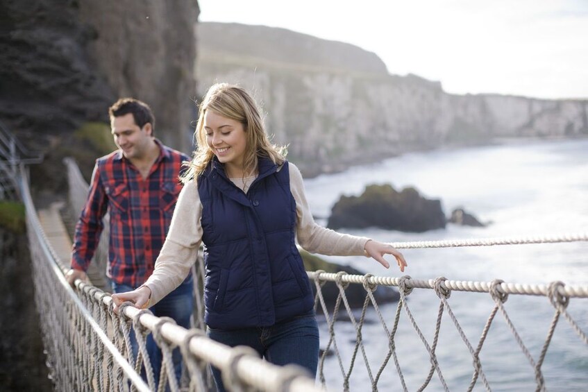 Couple walking across a bridge between cliffs in Ireland