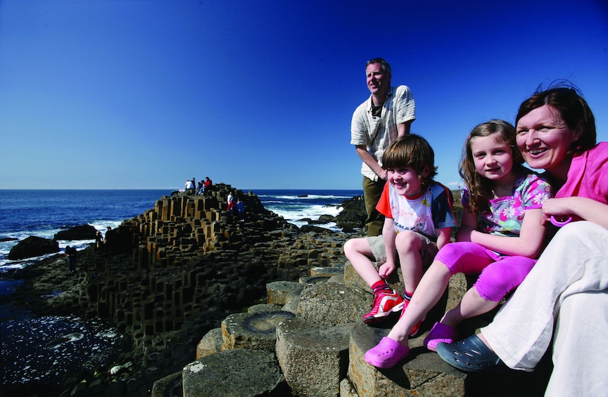 Family sitting on the rocks at Giants Causeway in Ireland