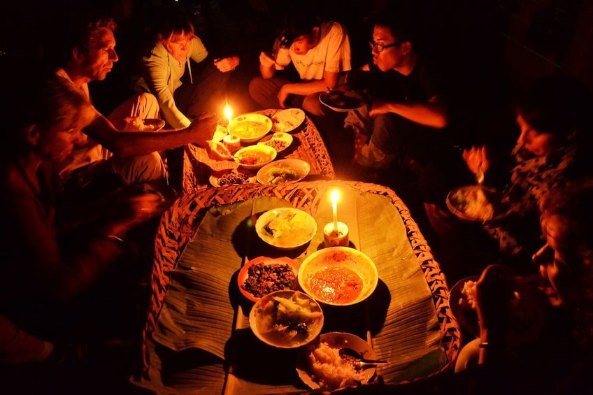 Group eats meal by candlelight in jungle in Nam Ha National Park
