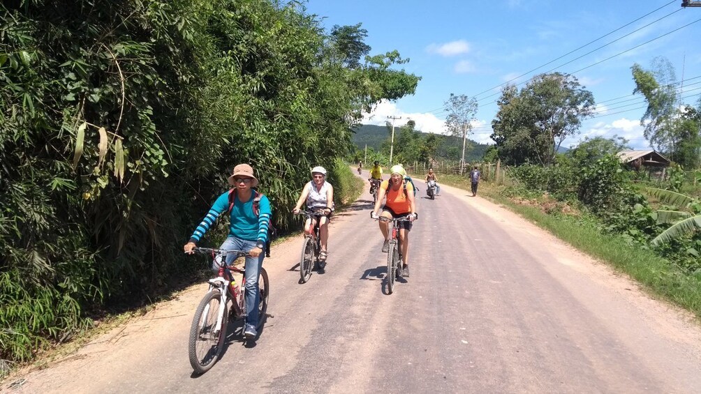 Tourists bike on road through Luang Nam Tha Valley, Laos