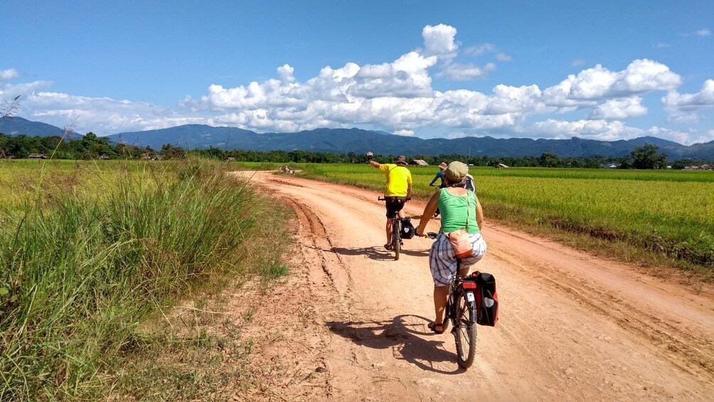 Tourists bike on dirt road through Luang Nam Tha Valley, Laos