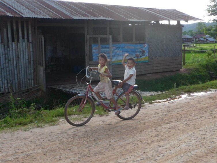 Two small children balance on a bike in village in Luang Nam Tha Valley, Laos