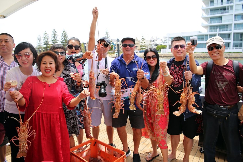 Show item 1 of 6. Group holding up lobsters in Australia