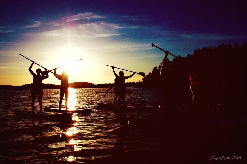 View of a group stand-up paddle-boarding under the midnight sun in Rovaniemi