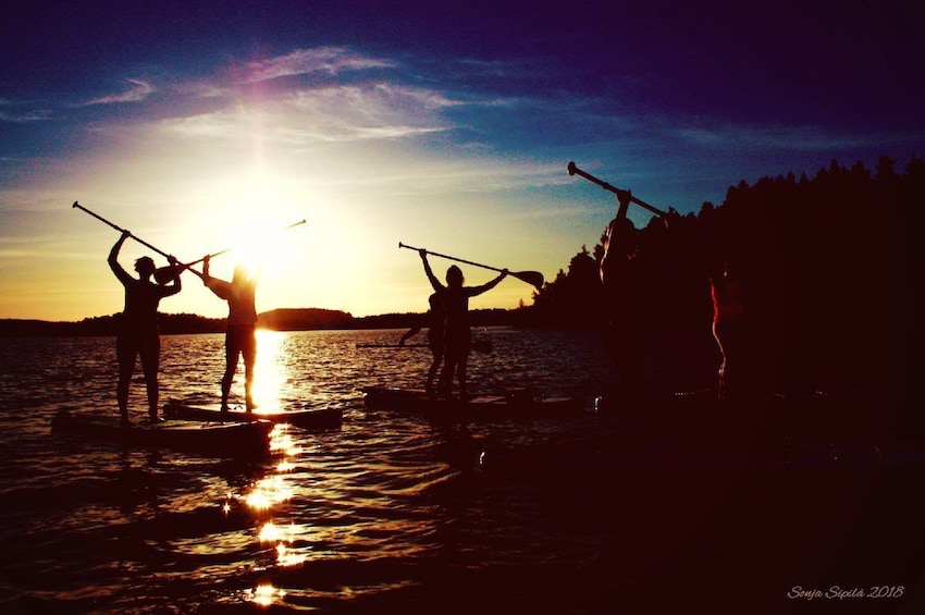 View of a group stand-up paddle-boarding under the midnight sun in Rovaniemi