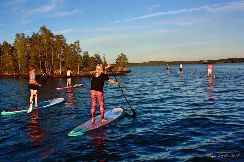 Group stand-up paddle-boarding under the midnight sun in Rovaniemi