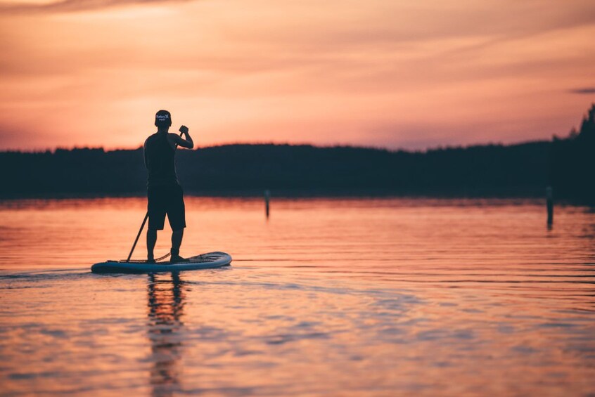 Man stand-up paddle-boarding under the midnight sun in Rovaniemi