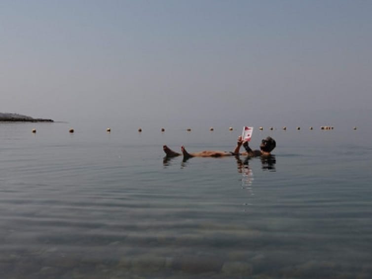 Man floating on the Dead Sea while reading a book