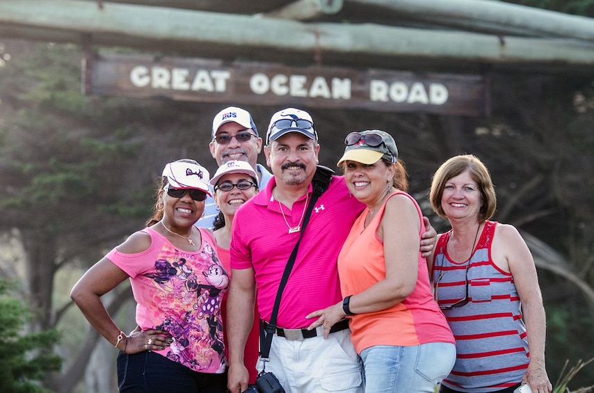 Tour group stands in front of a sign for the Great Ocean Road