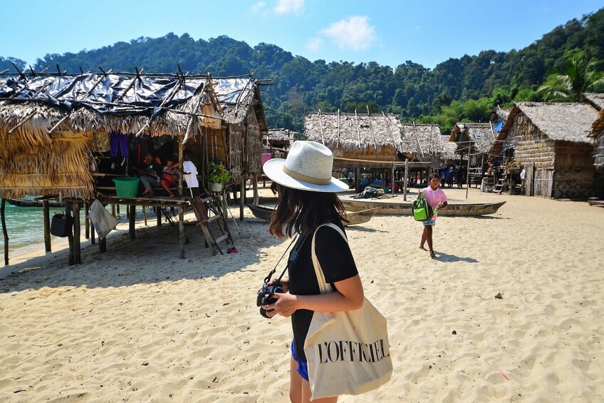Woman stands among huts of Moken Village