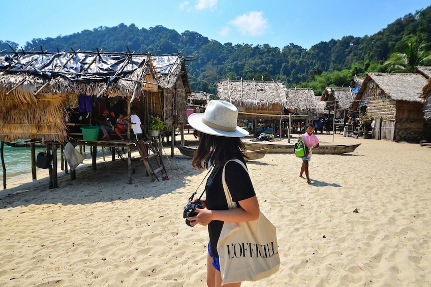 Woman stands among huts of Moken Village