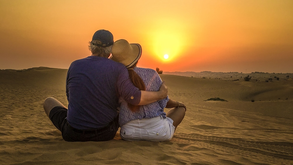 Couple sitting in the sand at sunset in Doha