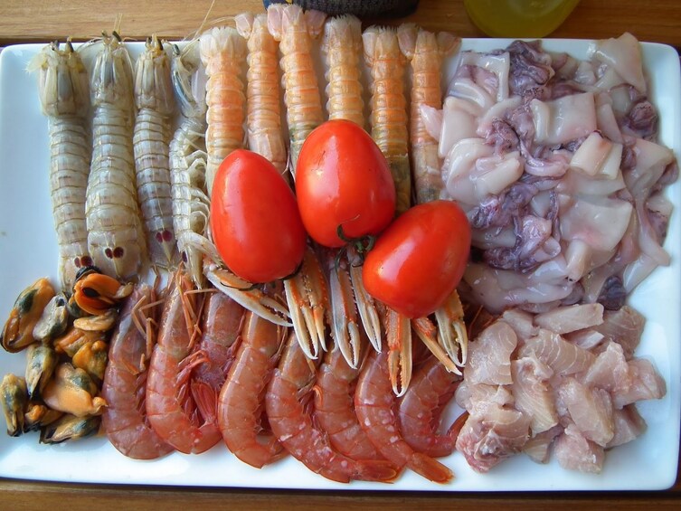 White platter of raw fish with tomato garnish