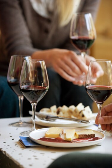Glasses of wine and charcuterie on table with woman holding wine glass in background