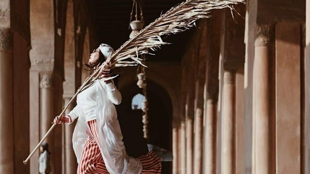 Woman walks with palm frond inside mosque in Cairo, Egypt