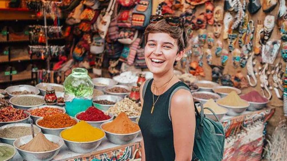 Woman smiles in front of spice display at Khan el Khalili Bazaar in Islamic Cairo, Egypt