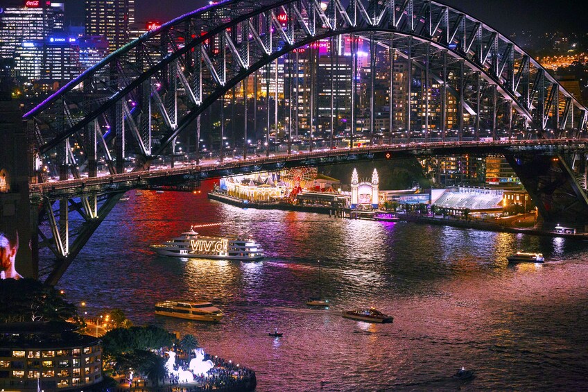 Boats under Sydney Harbour Bridge at night