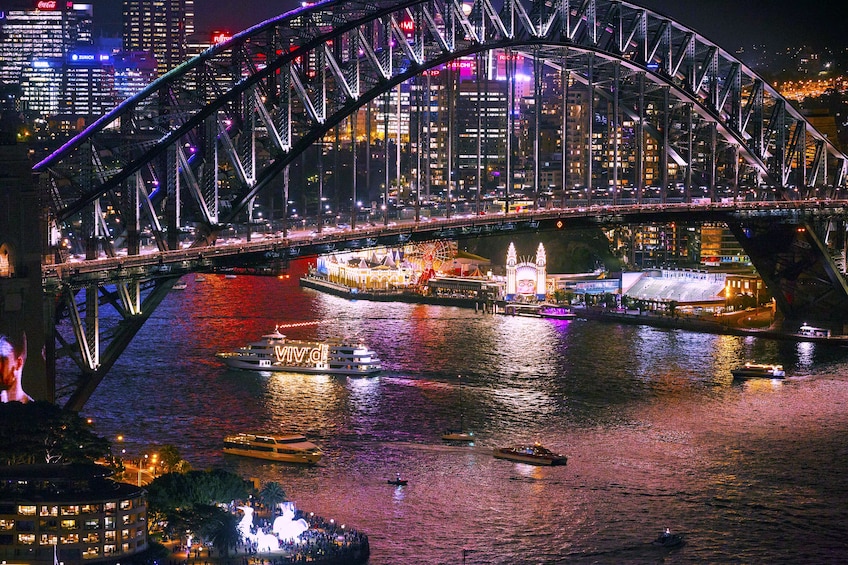 Boats under Sydney Harbour Bridge at night