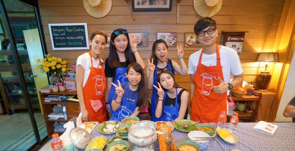 Group at a table full of freshly made Thai dishes at Sompong Thai Cooking School in Bangkok