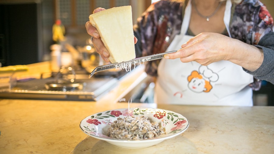 Woman grating cheese onto risotto in Trieste