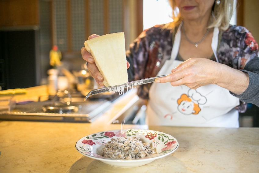 Woman grating cheese onto risotto in Trieste