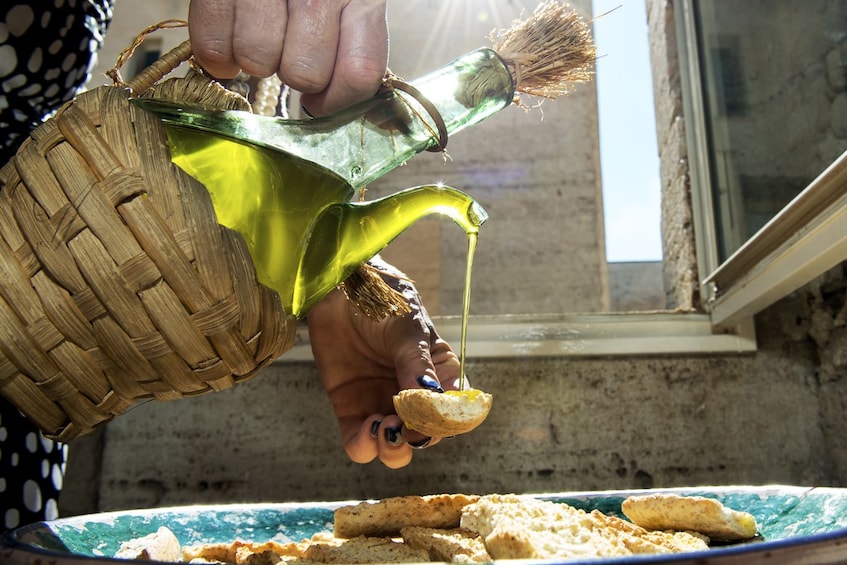 Show item 1 of 8. Woman pouring olive oil on bread in Cagliari