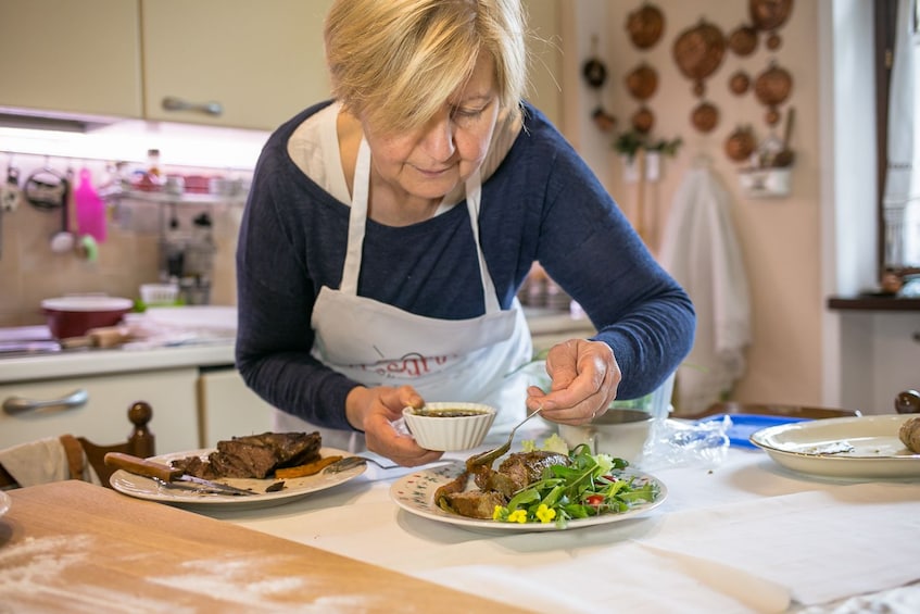 Woman preparing a meat and salad dish at a private cooking class in a local home in Turin