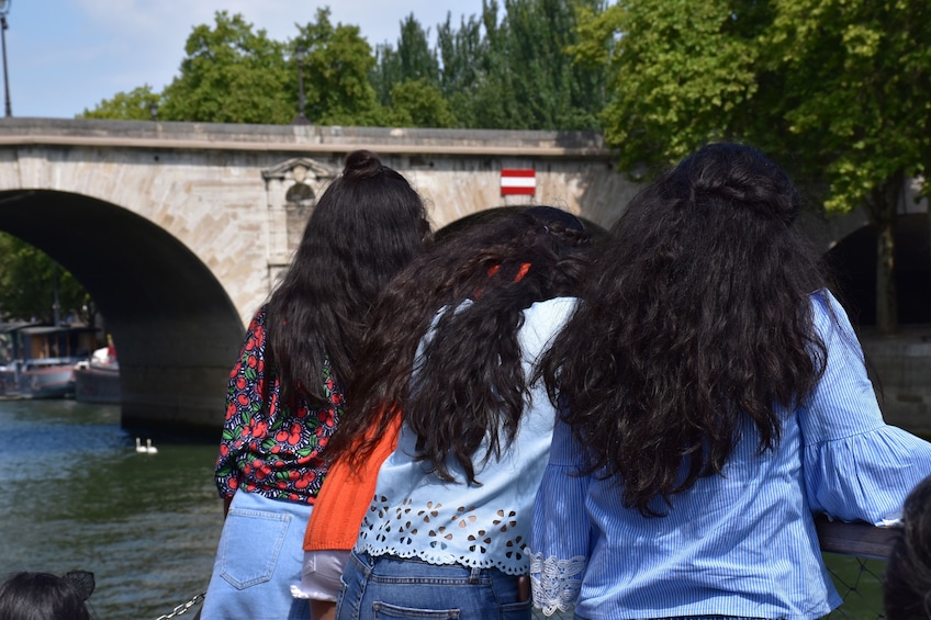 Three women look over the side of their boat in the Seine in Paris, France