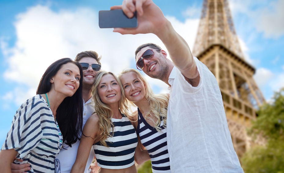 Group of friends take picture in front of the Eiffel Tower on a sunny day