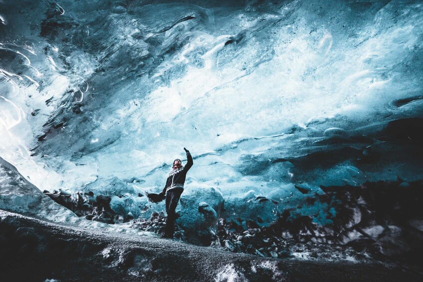 Man looks up at ceiling of ice cave in Iceland