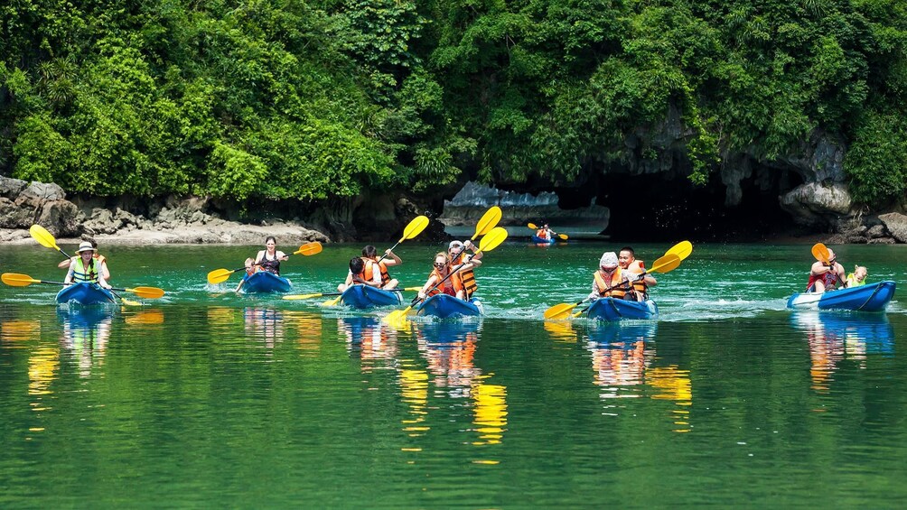 Tourists kayak in bright waters of Halong Bay