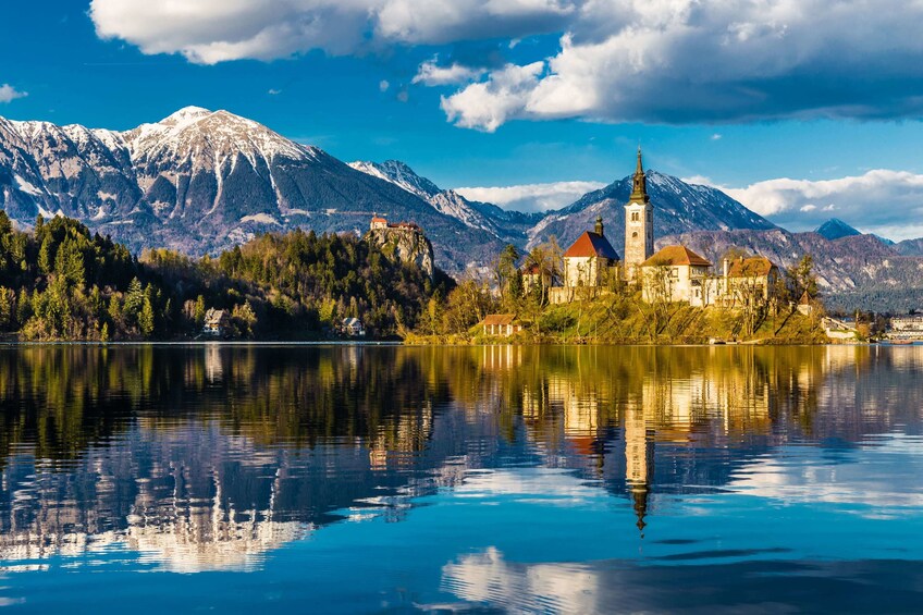 Island in Lake Bled with church and mountain range in the background