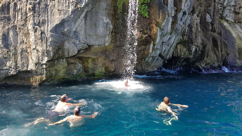 Show item 5 of 10. Tourists swim near cliffs of Capri, Italy