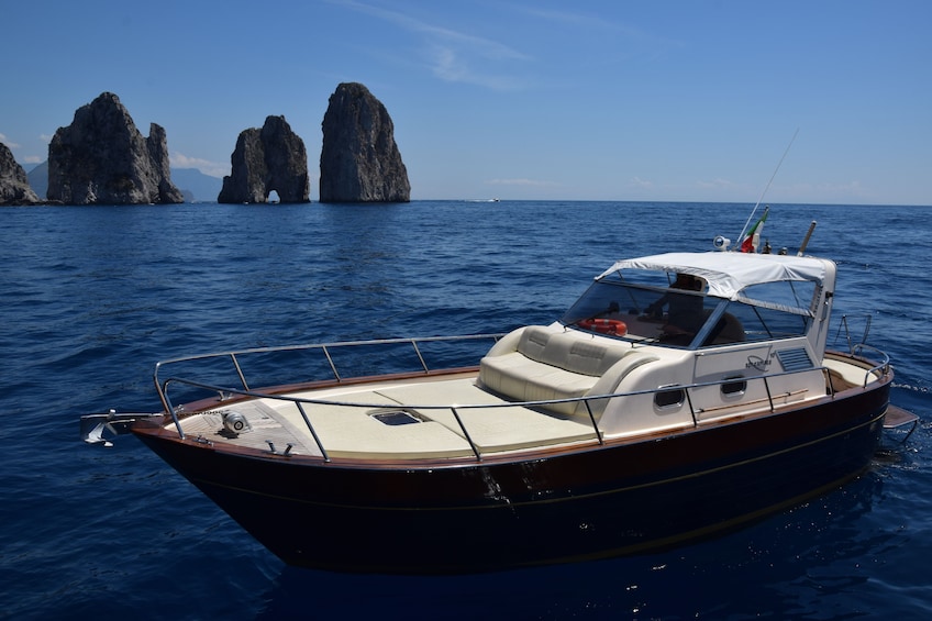 Show item 3 of 10. Small boat in water with islands of Capri in the background