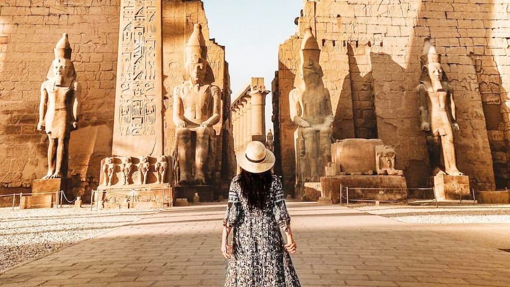 Woman stands in front of large tombs in Egypt