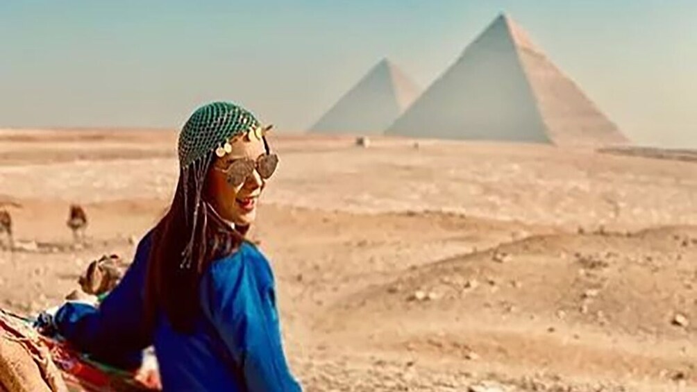 Woman looks over her shoulder in front of Pyramids of Giza