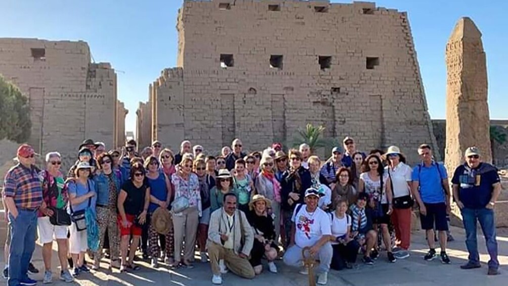 Large group of tourists pose in front of Temple of Horus at Edfu