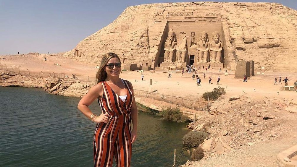 Woman poses in front of water and Abu Simbel Temples in Aswan, Egypt