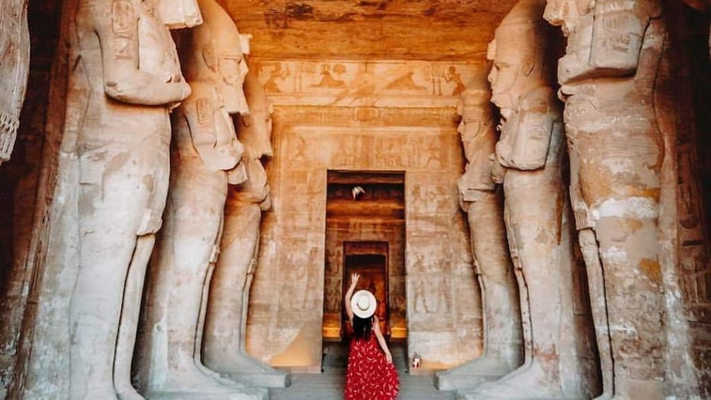 Woman poses in front of doorway to Abu Simbel Temples with statues on either side