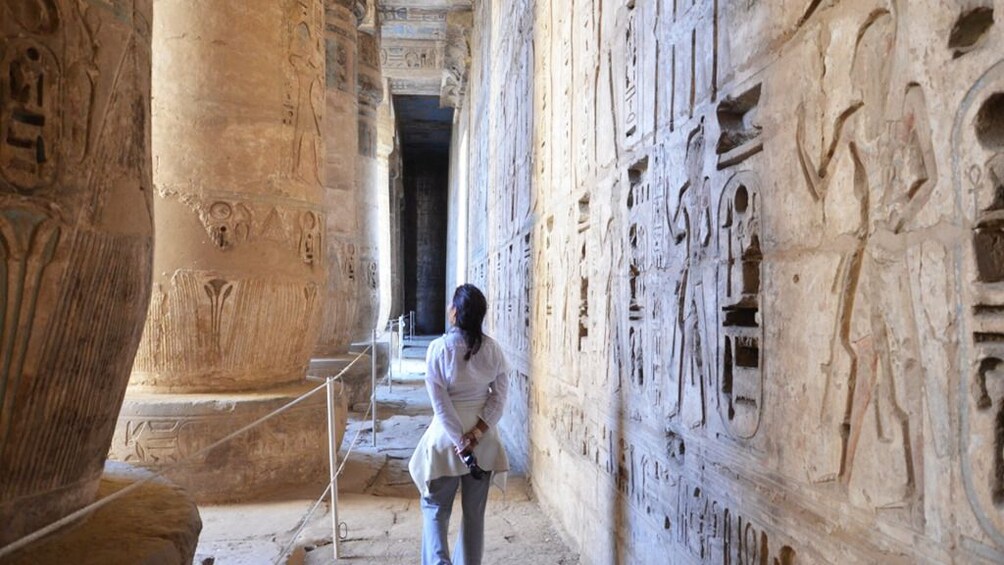 Woman looks around at engraved columns in Egyptian tomb