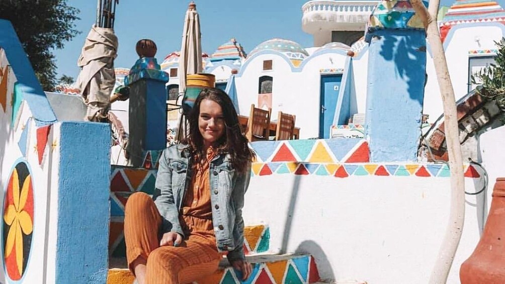 Woman sits on colorful stairs of Nubian Village in Egypt