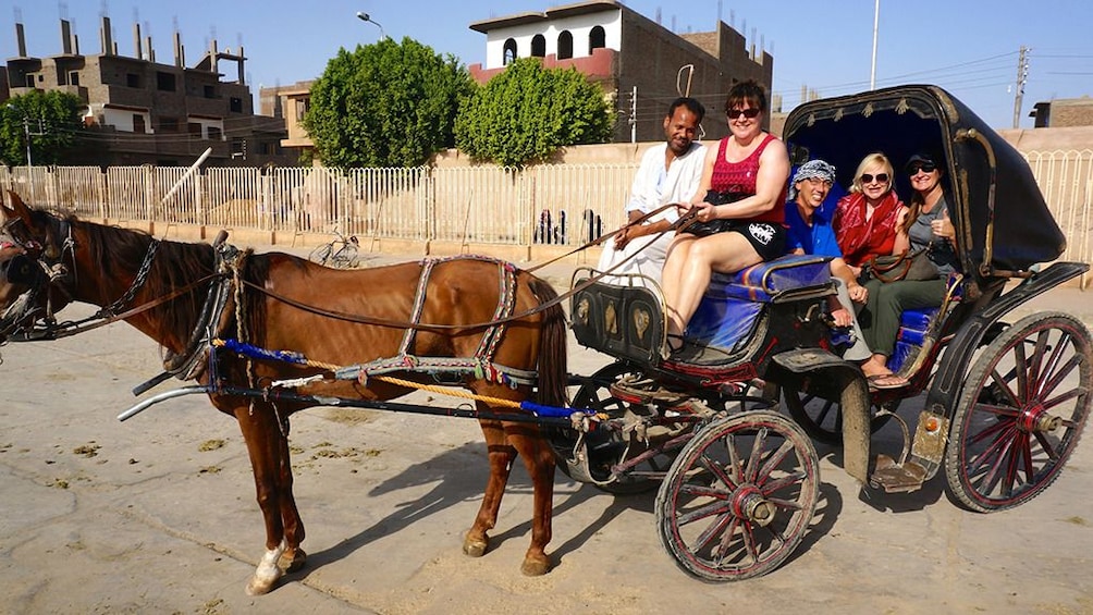 Many tourists pose in carriage with one holding the reins