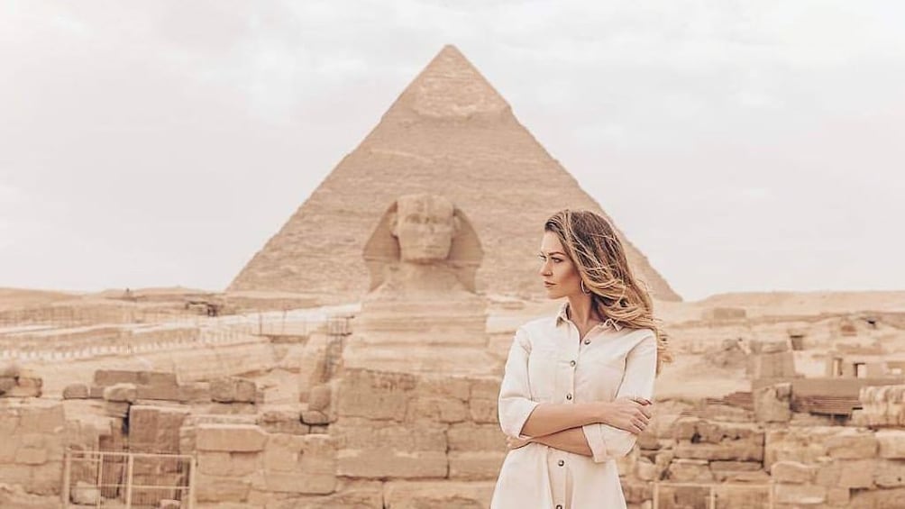 Woman poses with sphynx and pyramid in the background